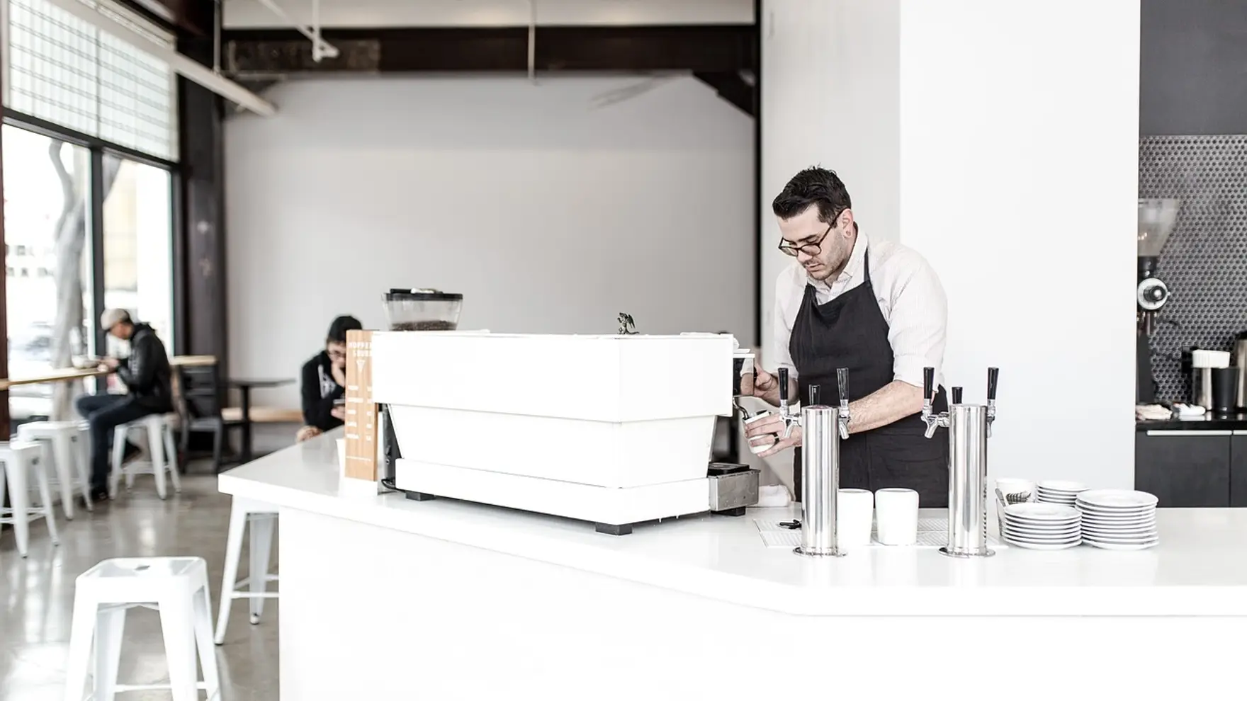 A barista making coffee behind the counter of a small café