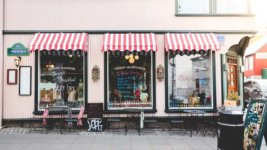 The front of a small bistro with striped awnings and chalkboard menus